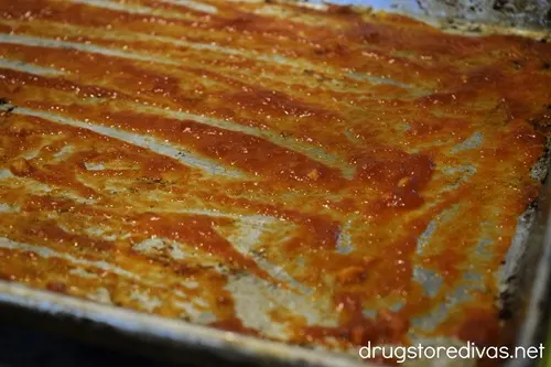 A thin layer of marinara sauce at the bottom of a sheet pan.