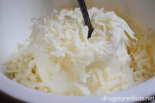Ricotta cheese and shredded mozzarella cheese in a white bowl with a spoon.