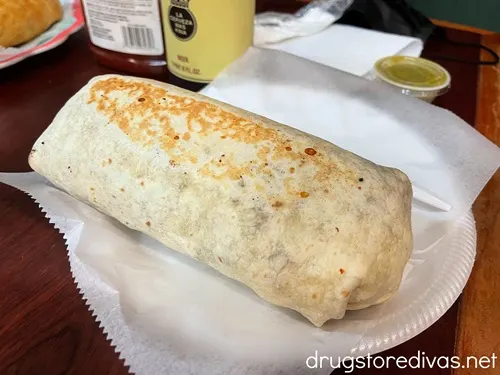 A burrito on a foam plate on a table.