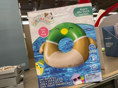 A duck shaped pool float in a box on a shelf in a store.