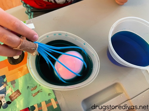 A kid's hand dying Easter eggs.