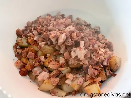 Cooked diced potatoes and ham in a white bowl.