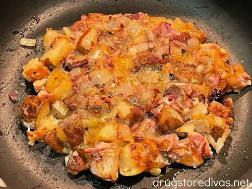 Semi-cooked potato and ham hash in a pan.