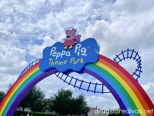 A rainbow with a roller coaster track on it and a cloud that says "Peppa Pig Theme Park" with a cartoon pig on top.