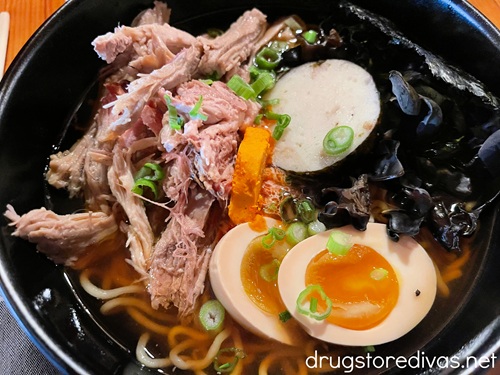 A bowl of ramen with noodles, pork, and a hard boiled egg.