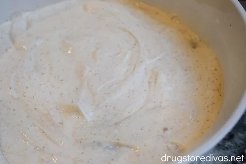 A layer of seasoned sour cream in a white, round casserole pan.