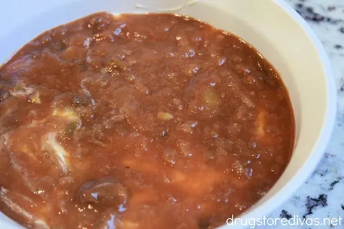 A layer of salsa in a white, round casserole pan.