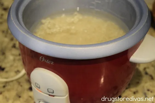 Rice cooking in a red rice cooker.