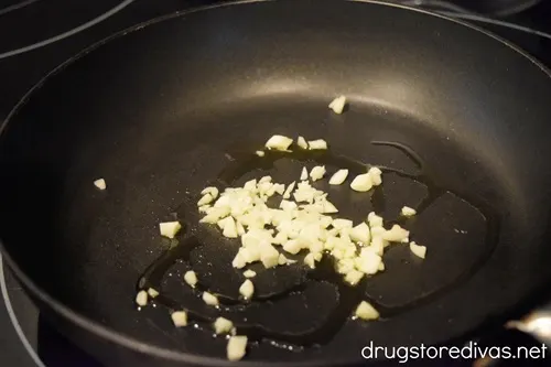 Chopped garlic and olive oil in a black pan.