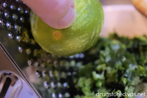 A lime being zested on a grater.