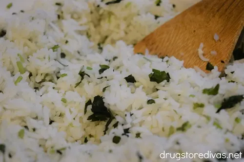 A bamboo spoon stirring cilantro lime rice.