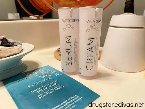 Two bottles of skin care products and a sheet mask from Factor Five on a bathroom counter.