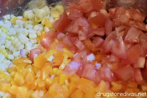 Diced orange bell pepper, Roma tomatoes, and corn kernels in a bowl.