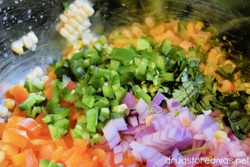 Diced orange bell pepper, Roma tomatoes, red onion, corn kernels, jalapeno peppers, and fresh cilantro in a bowl.