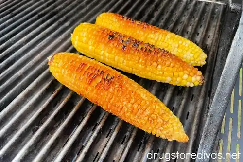Three pieces of corn with a little char on a grill.