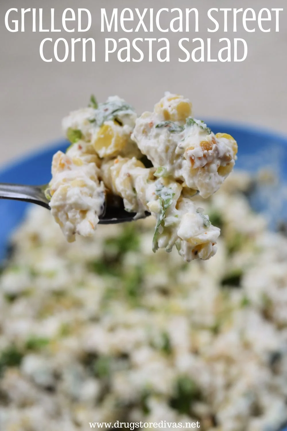 A spoon holding a spoonful of pasta salad with corn over a bowl filled with pasta salad and the words 