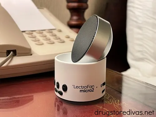 A mini white noise machine on a desk in a hotel room.
