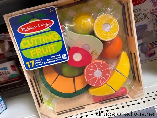 A Melissa & Doug wooden fruit cutting set in a package on a shelf.