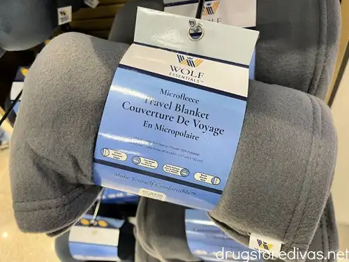 A gray travel blanket on a hook at a store.