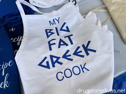 A white apron that says "My Big Fat Greek Cook" in blue letters.