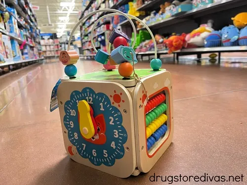 A wooden cube toy on the floor in a store.