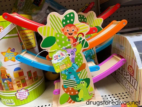 A wooden race track play set, painted with colorful animals on it, on a shelf in the store.