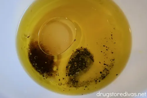 Olive oil with seasoning in a white bowl.