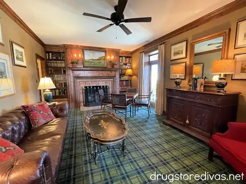 The inside of the lobby at Clark's Inn in Santee, SC, featuring a brown couch, brown bookcases with a fireplace between them, a set of table and chairs, another table, a red couch, and a blue patterned floor.