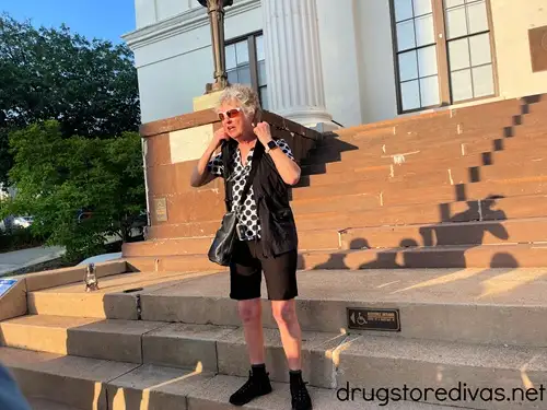 A woman in a black polka dot shirt with black shorts standing on the steps of Thalian Hall in Wilmington, NC.