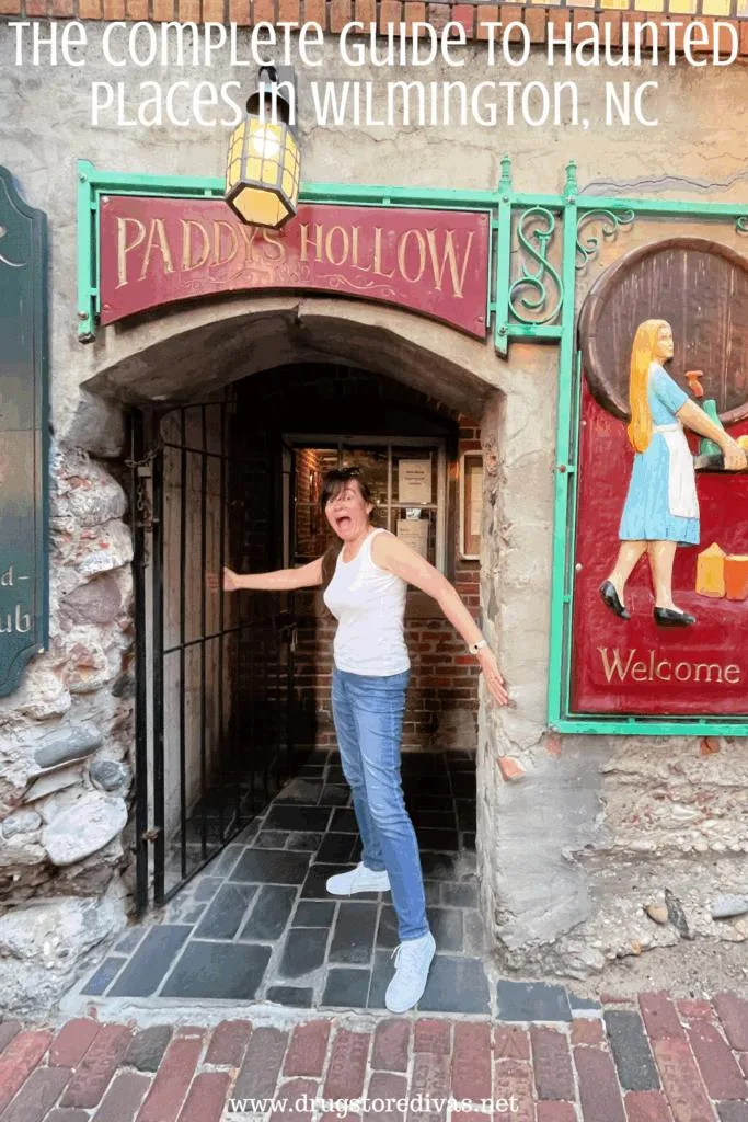 A woman in a white tank top and jeans in an entryway to a restaurant called Paddy's Hollow with the words "The Complete Guide To Haunted Places In Wilmington, NC" digitally written above her.