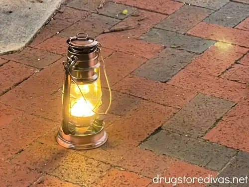 A camping lantern on a brick floor.