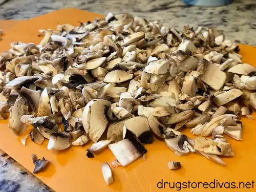 Diced mushrooms on an orange cutting board.