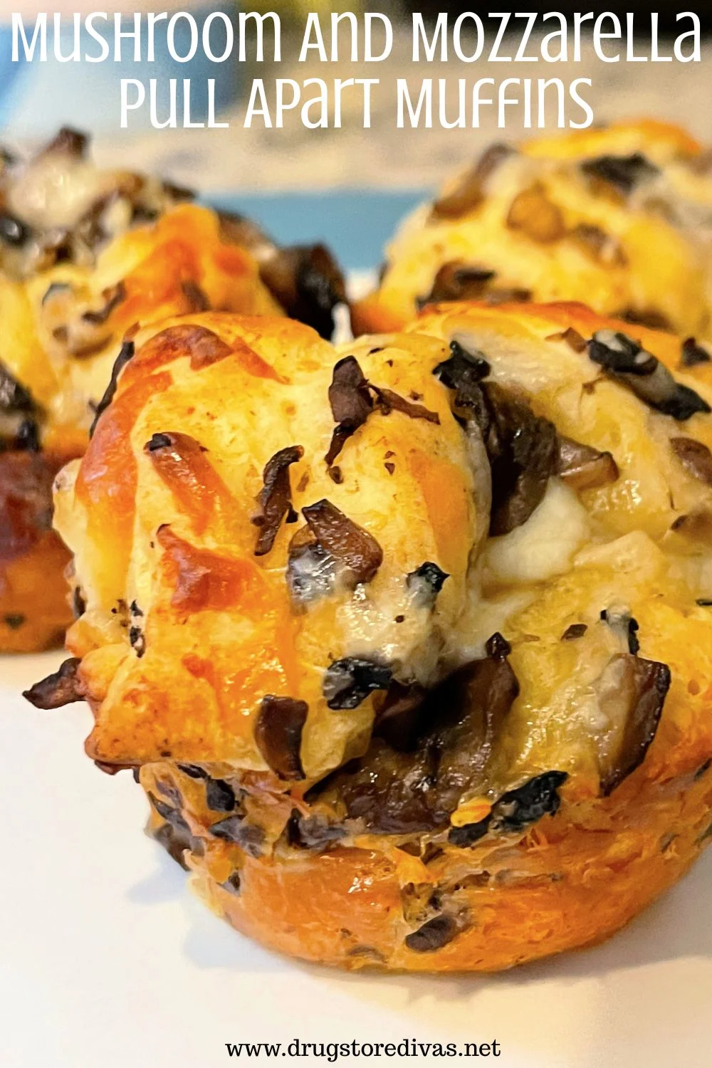 Three muffins with mushrooms and cheese in them on a white and blue plate with the words 