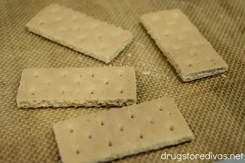 Four individual graham cracker pieces on a silicon baking mat.