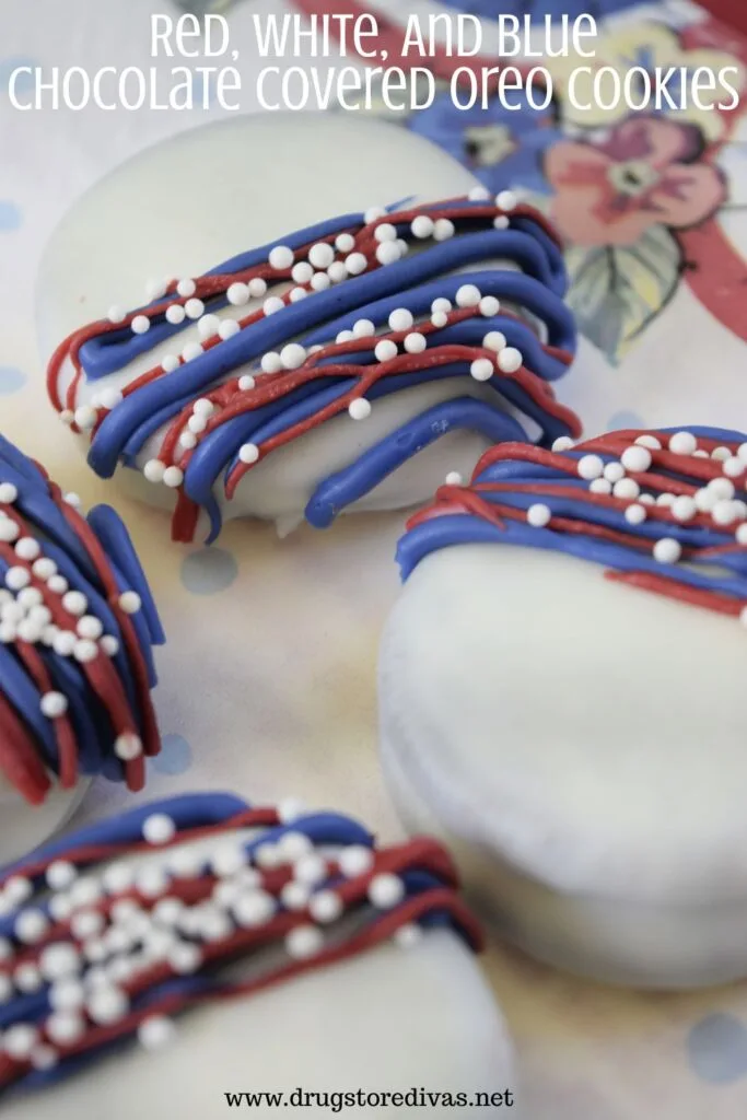 Four white Oreo cookies with blue and white lines and white nonpareil sprinkles on them on a white napkin with the words "Red, White, And Blue Chocolate Covered Oreo Cookies" digitally written above them.