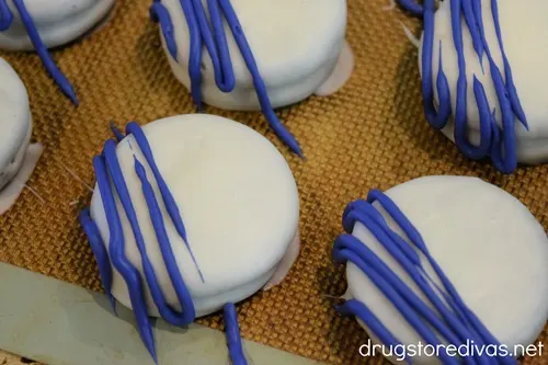 White Oreo cookies with blue lines piped across half the cookie.