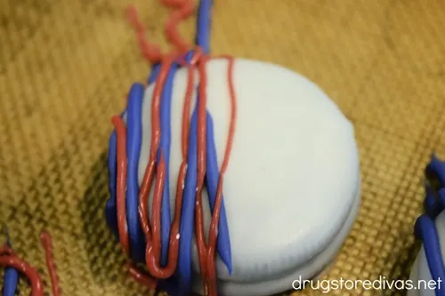 White Oreo cookies with blue and red lines piped across half the cookie.