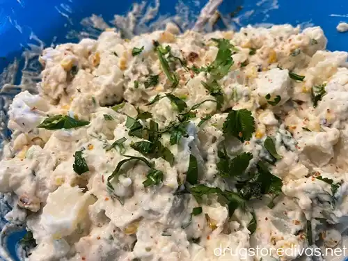 Mexican Street Corn Potato Salad, garnished with cilantro and Tajin seasoning, in a blue bowl.