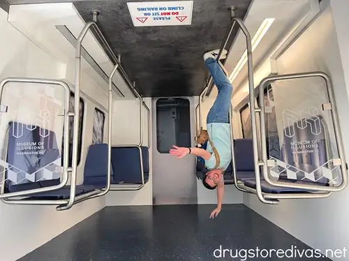 A man in a blue t-shirt who looks like he's hanging upside down in a subway from the Museum of Illusions in Washington, DC.