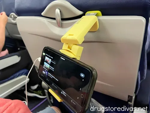 A yellow phone mount clipped into an airline tray and holding a phone.