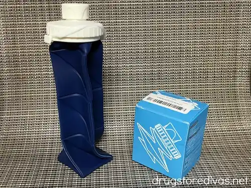 A navy blue collapsible water bottle next to its box.