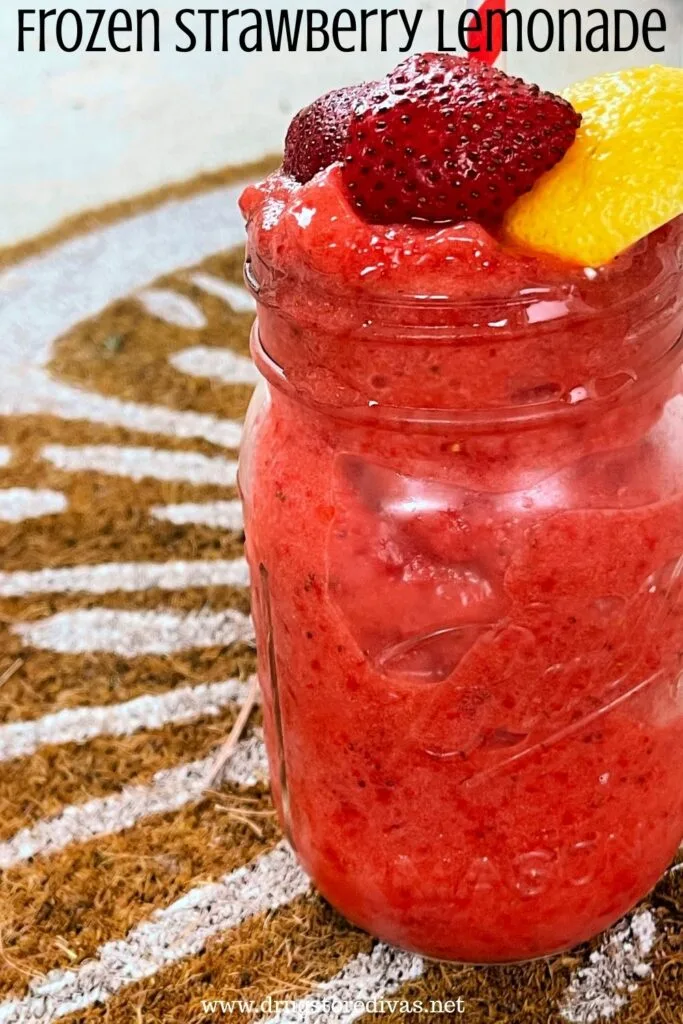 A mason jar filled with a red frozen drink with strawberries and lemon on top and the words "Frozen Strawberry Lemonade" digitally written on top.