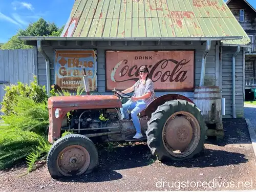 A woman on a tractor with a vintage Coca-Cola sign behind her at Mast General Store in North Carolina.
