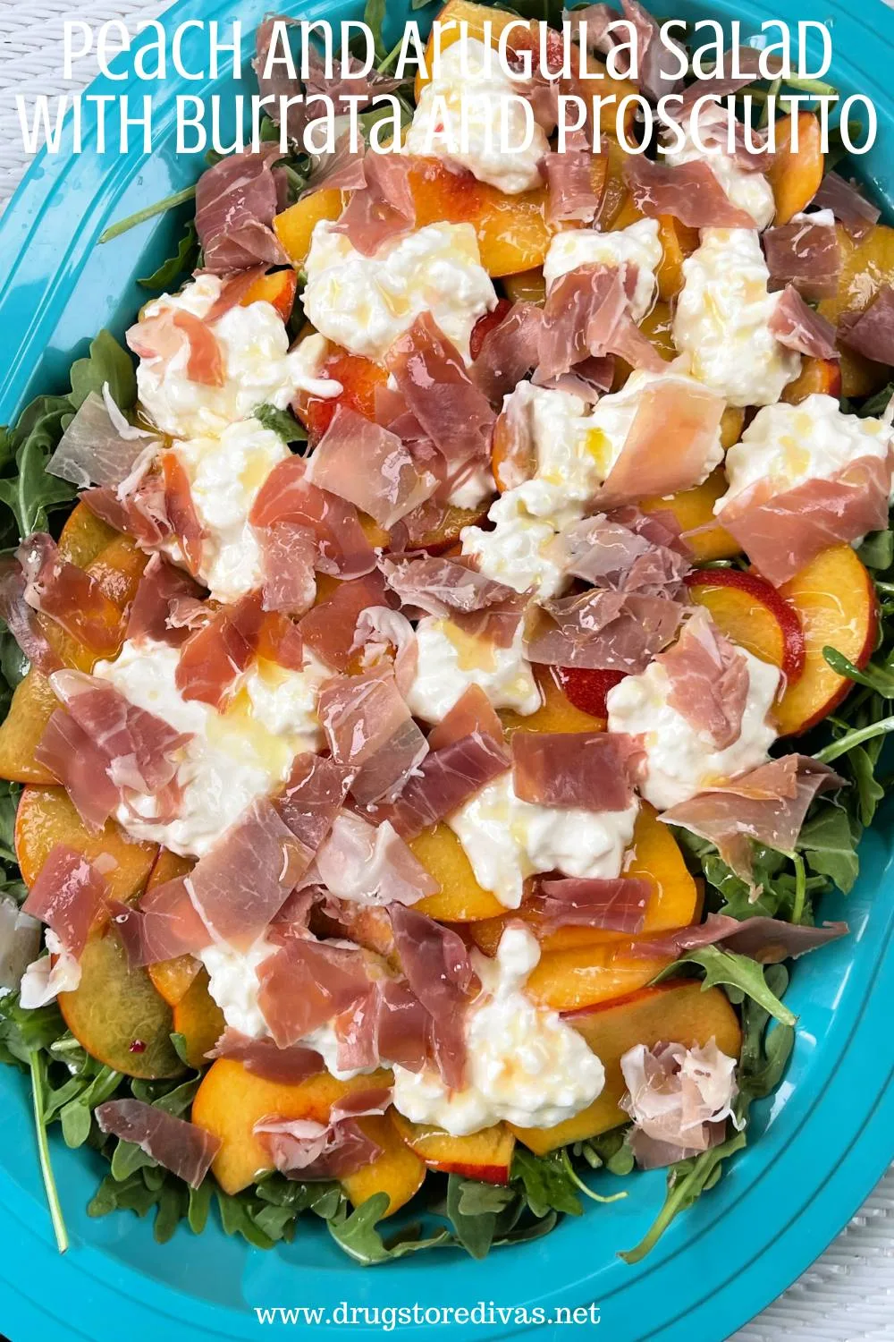 A blue, oval tray filled with a salad of arugula, peaches, burrata cheese, and prosciutto with the words 