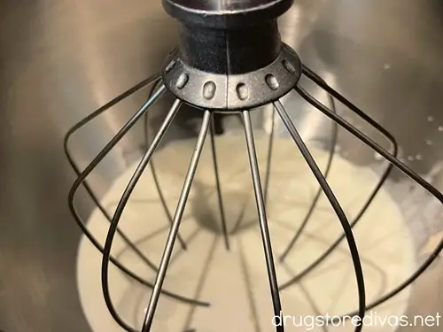 Heavy cream in the bottom of a stand mixer bowl with the whisk attachment.