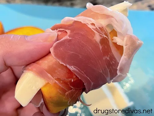 Prosciutto wrapped around a peach slice and a mozzarella slice.