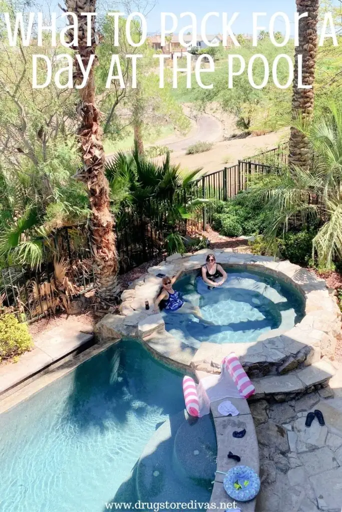 Two women sitting in a hot tub that's attached to an inground pool with the words "What To Pack For A Day At The Pool" digitally written above them.