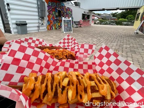 Three Korean Corn Dogs on red and white checkered paper in front of Astro Dogs restaurant in The Cargo District in Wilmington, NC.