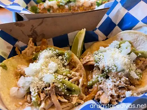 Two chicken tacos with elote behind them on blue and white checked paper from Beat Street in The Cargo District in Wilmington, NC.
