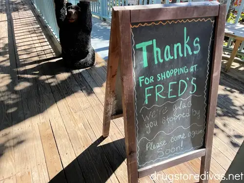 A chalkboard sign on a wooden deck thanking you for visiting Fred's General Mercantile in Beech Mountain, NC.